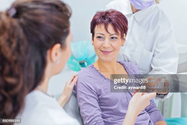dentist showing teeth dentures to a patient - equipamento dentário imagens e fotografias de stock