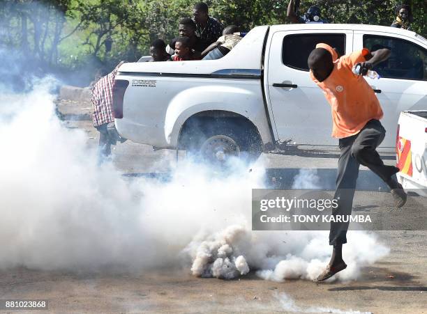 Supporters of Kenya's opposition leader flee from teargas fired by anti-riot police on November 28 during demonstrations in Umoja suburb of Nairobi,...