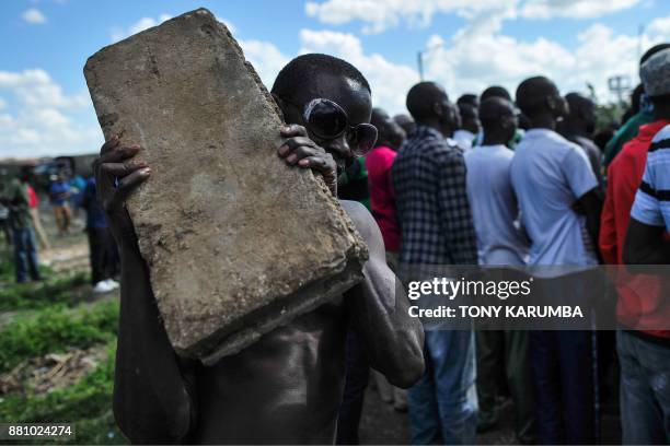 Supporter of Kenya's opposition leader poses with a concrete block supporters listens to a leader's road-side address in Umoja suburb of Nairobi,...