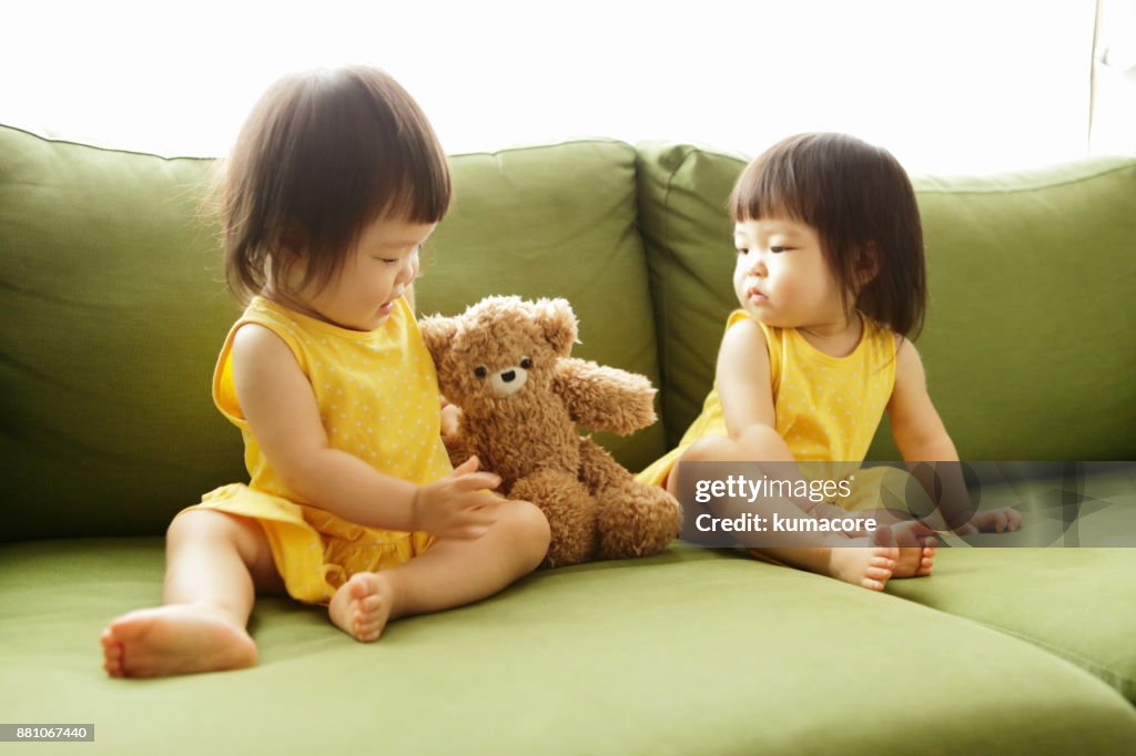 Twin little sisters playing with a teddy bear