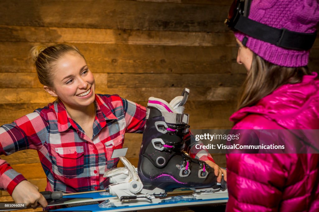 Female Sales Assistant tuning up skis for customer.