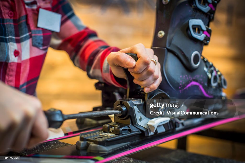 Sales Assistant adjusting ski boots and binding on skis.