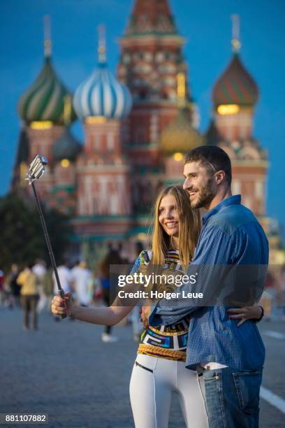 handsome couple takes selfie photograph at red square with st. basil's cathedral at dusk, moscow, russia - selfie stick stock pictures, royalty-free photos & images