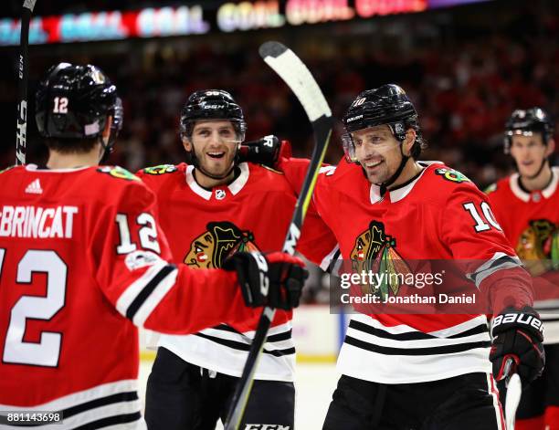 Ryan Hartman and Patrick Sharp of the Chicago Blackhawks skate in to congratulate Alex DeBrincat after DeBrincat scored his second goal of the game...