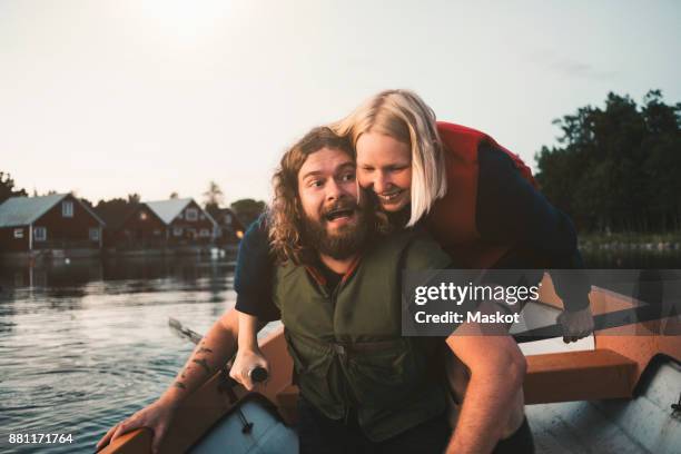 happy couple enjoying in boat on lake against sky - mischief stock pictures, royalty-free photos & images