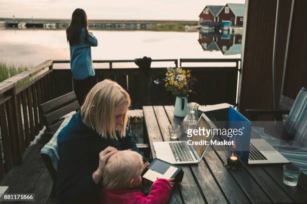 woman teaching daughter in using digital tablet while friend talking on mobile phone - holiday home decor stock pictures, royalty-free photos & images