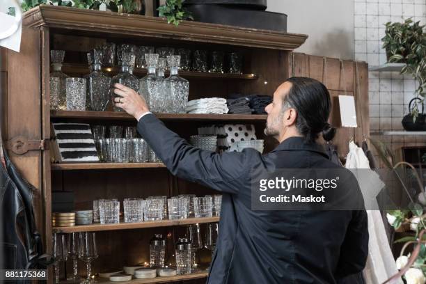 rear view of mature man choosing glass container from shelf at store - tool rack ストックフォトと画像