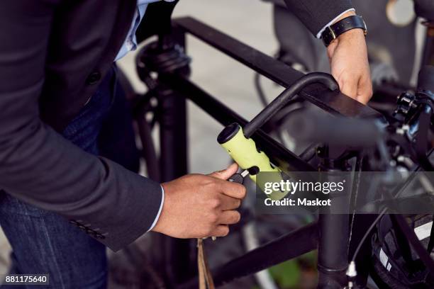 midsection of man locking bicycle in city - bicycle lock stock pictures, royalty-free photos & images