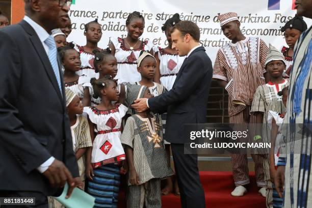 French President Emmanuel Macron speaks with a child as he visits the Lagm Taaba school on November 28 in Ouagadougou, as part of his first African...