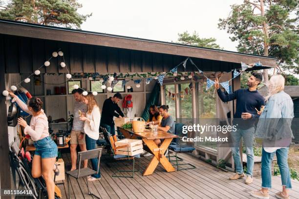 young male and female friends preparing for party at cottage - patio party stock pictures, royalty-free photos & images