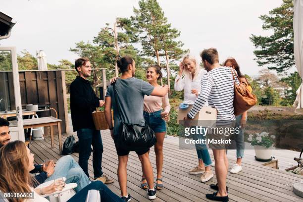 happy friends greeting each other on cottage deck - mas photos et images de collection
