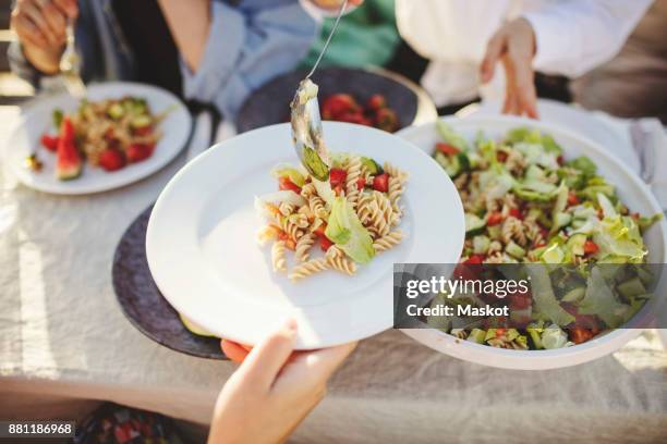close-up of woman serving pasta to friend at picnic table - serving size stock pictures, royalty-free photos & images