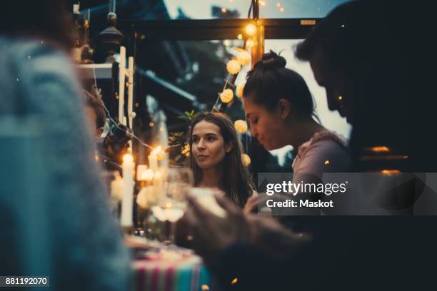 multi-ethnic young friends sitting in conservatory during dinner party - dinner party at home stockfoto's en -beelden