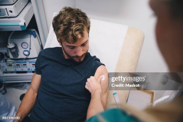 cropped image of female nurse injecting male patient at hospital - man touching shoulder stock pictures, royalty-free photos & images