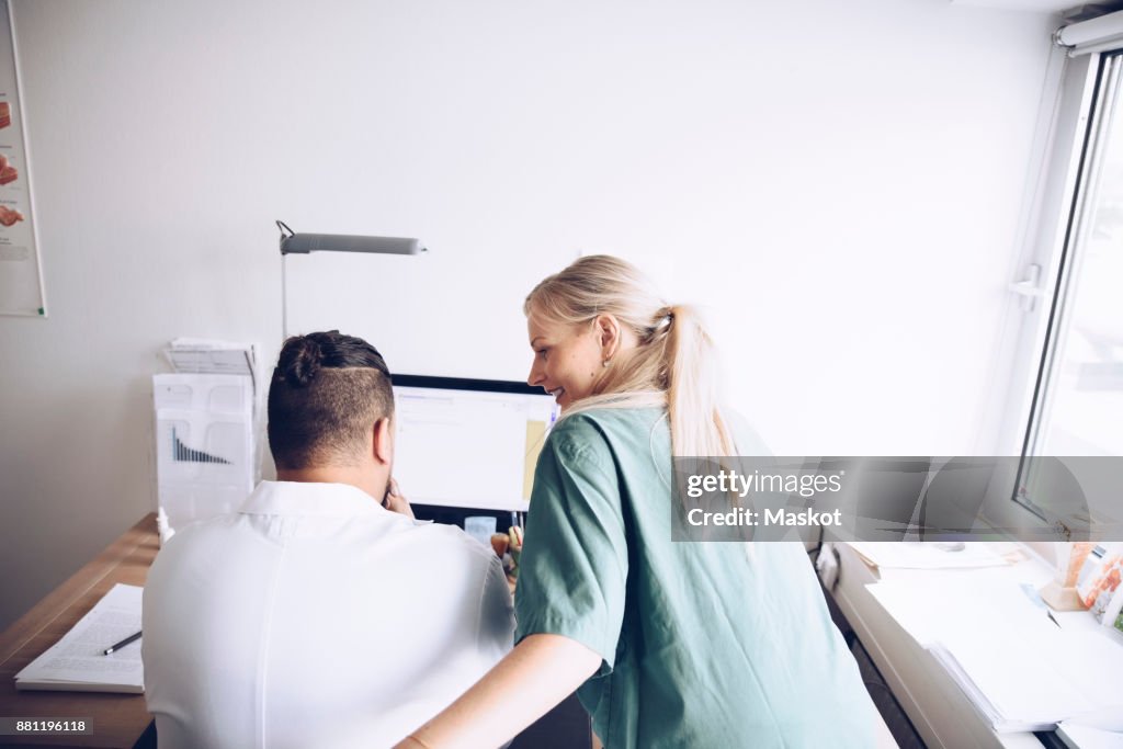 Rear view of female nurse and male doctor discussing at office in hospital