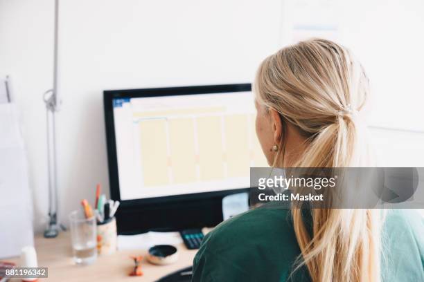 rear view of female nurse working at computer desk in office - bakifrån bildbanksfoton och bilder