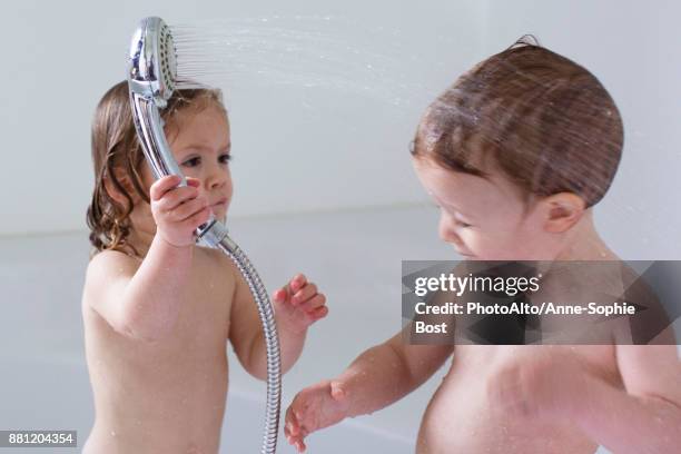 children playing in bathtub - brother sister shower stock-fotos und bilder