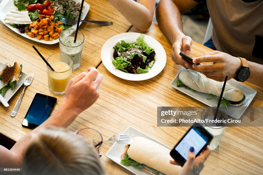 Friends Using Smartphones While Eating In Restaurant High-Res Stock ...