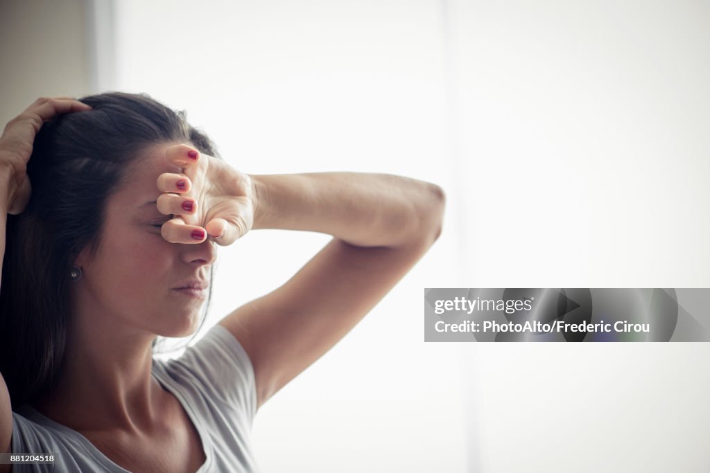 Young woman holding one hand on forehead