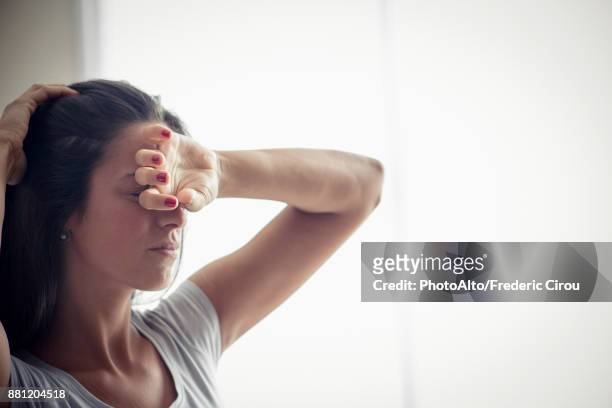 young woman holding one hand on forehead - head aches stock pictures, royalty-free photos & images
