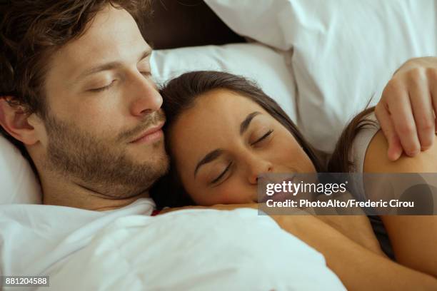 couple resting and embracing in bed - romantic young couple sleeping in bed stock pictures, royalty-free photos & images