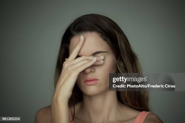 young woman covering her eyes with one hand - augen zuhalten stock-fotos und bilder