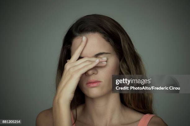 young woman covering her eyes with one hand - hands covering eyes stock pictures, royalty-free photos & images