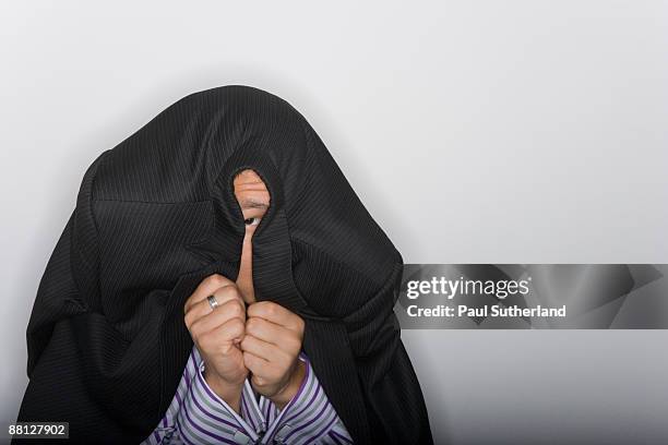 young businessman peeping out from under his jacke - den kopf in den sand stecken stock-fotos und bilder