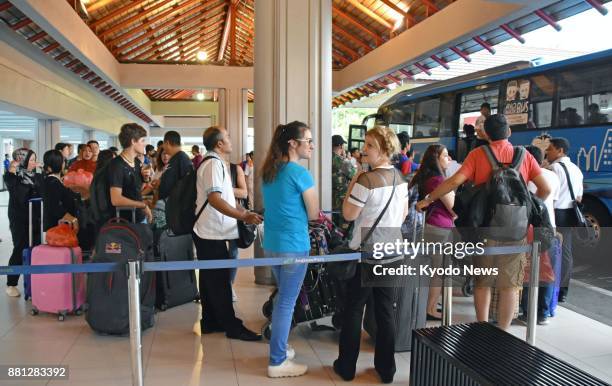 Tourists wait for a bus at Bali airport in Indonesia on Nov. 28, 2017. Authorities have closed the airport in the wake of an eruption of Mt. Agung....