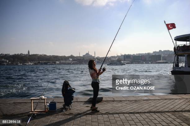 Woman is fishing next to the bosphorus river on November 15, 2017 at Karakoy district in Istanbul. / AFP PHOTO / OZAN KOSE
