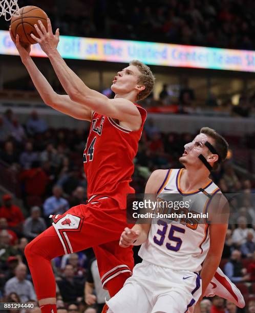 Lauri Markkanen of the Chicago Bulls goes up for a shot over Dragan Bender of the Phoenix Suns at the United Center on November 28, 2017 in Chicago,...