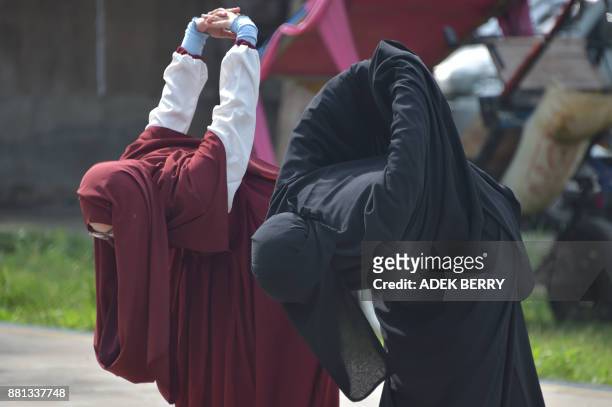 This picture taken on November 12, 2017 shows two Indonesian Muslim women stretching prior to taking archery lessons in Bekasi. Riding a horse or...