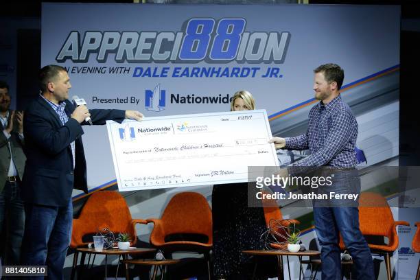 Jim McCoy of Nationwide presents a check to Dale Earnhardt Jr. And his wife Amy to help launch a fund to benefit Nationwide Childrens Hospital during...