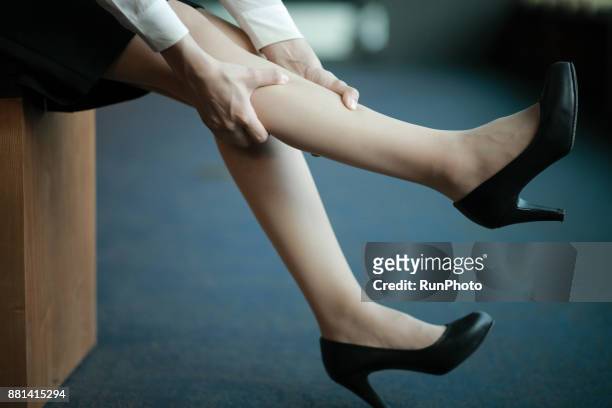 woman in heels massaging tired legs - kuit menselijk been stockfoto's en -beelden