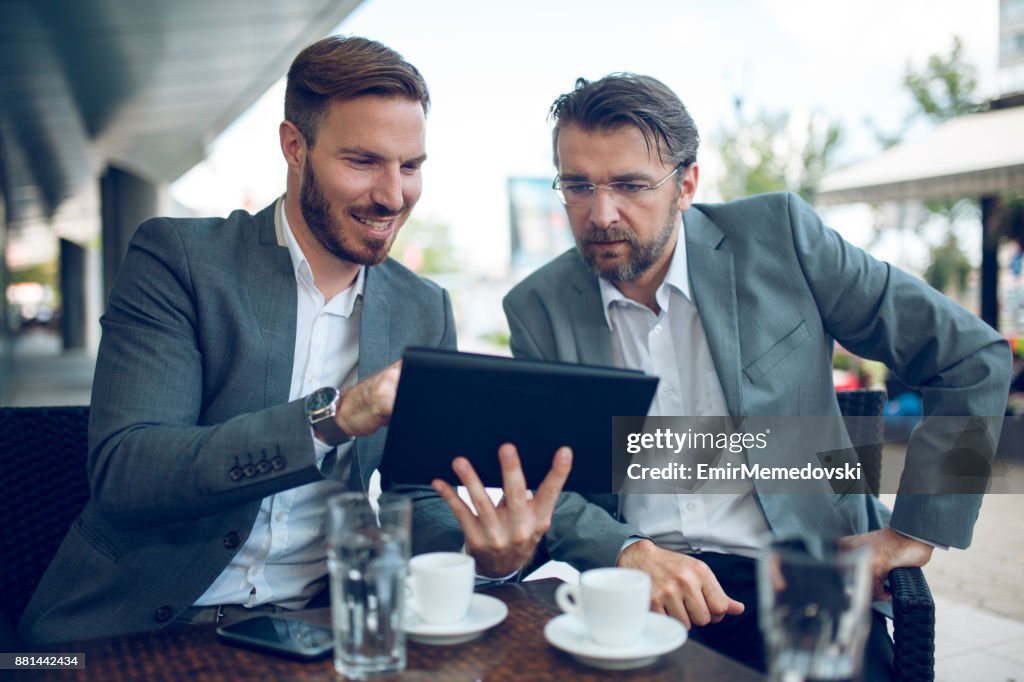 Young businessman cooperating with senior colleague outdoors.