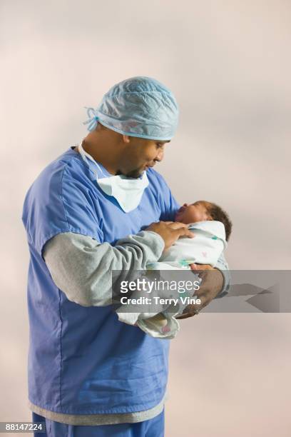 african doctor looking at newborn baby - funny surgical masks stockfoto's en -beelden