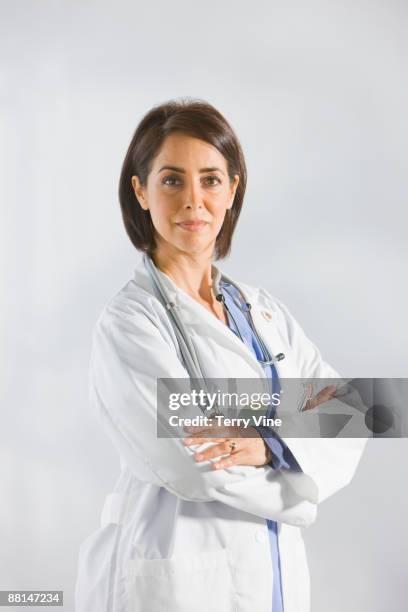 hispanic doctor in lab coat with arms crossed - female doctor on white stock pictures, royalty-free photos & images