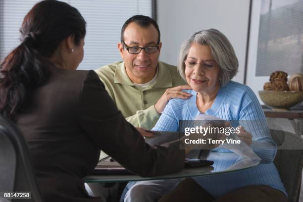 hispanic man helping mother read sales contract - petits caractères photos et images de collection