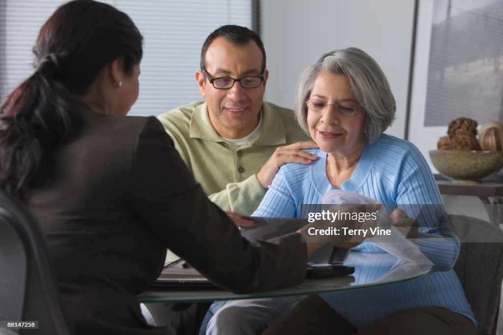 Hispanic man helping mother read sales contract