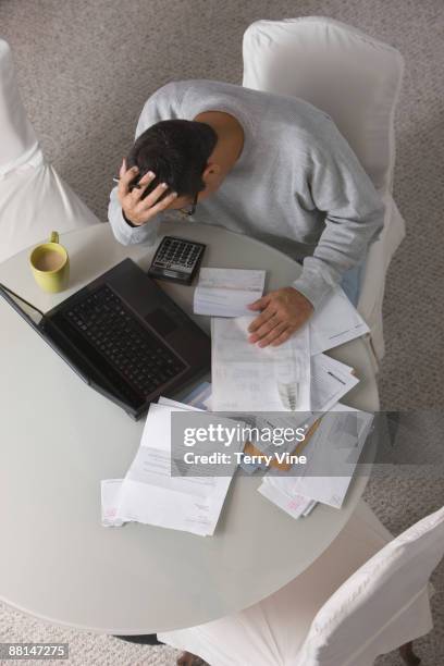 overhead view of frustrated hispanic man paying bills - paperwork frustration stock pictures, royalty-free photos & images