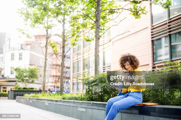 businesswoman using tablet computer outdoors - afro caribbean and american stock pictures, royalty-free photos & images