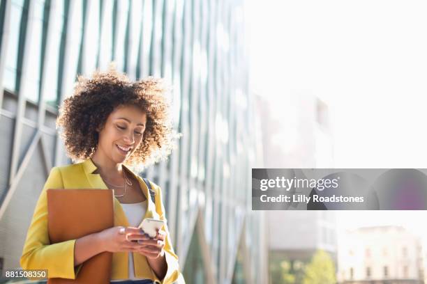 one woman only texting in city - abrigo amarillo fotografías e imágenes de stock