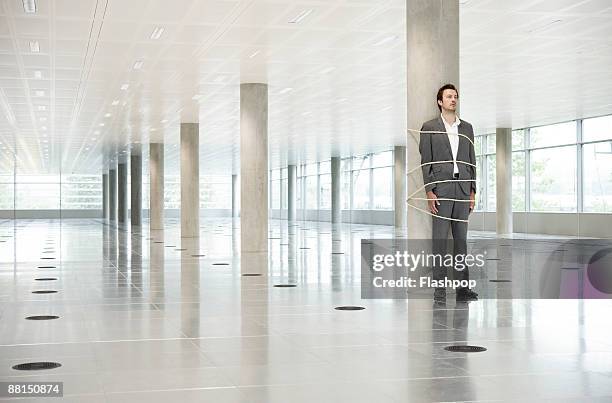 portrait of business man tied to pillar - amarrado fotografías e imágenes de stock