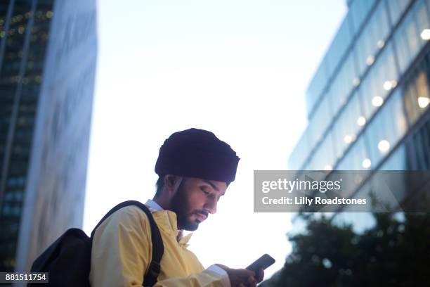 sikh man texting in city at susk - business man texting stock pictures, royalty-free photos & images