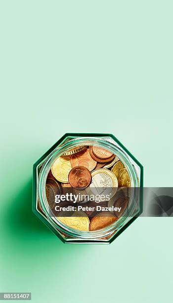 euro coins in savings jar. - saving for a rainy day englische redewendung stock-fotos und bilder