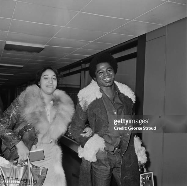 American singer-songwriter, musician and producer James Brown with his wife Deidre 'Deedee' Jenkins, at Heathrow Airport, London, UK, 10th March 1971.