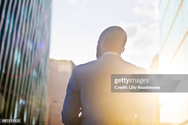 businessman walking towards sunset/sunrise - black jacket photos et images de collection