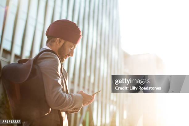 sikh man using mobile phone in modern city environment - turban stock pictures, royalty-free photos & images