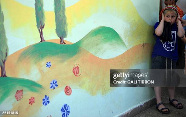 An Israeli schoolboy covers his ears as he makes his way to a bomb shelter at a school in Jerusalem after sirens sounded across Israel as part of a...