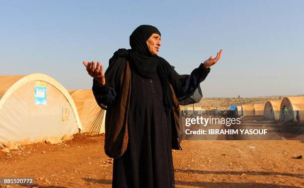 An elderly woman gestures as she stands outside tents at the Furat camp for the displaced from Deir Ezzor, north of the town of Kafr Dariyan in the...